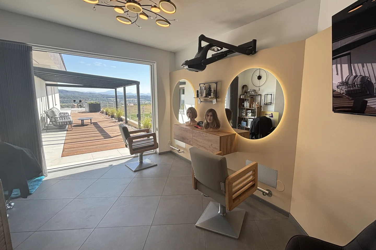 Salon Le Figaro in Mampasberg mit beleuchteten Spiegeln und Blick auf die Terrasse und die Landschaft